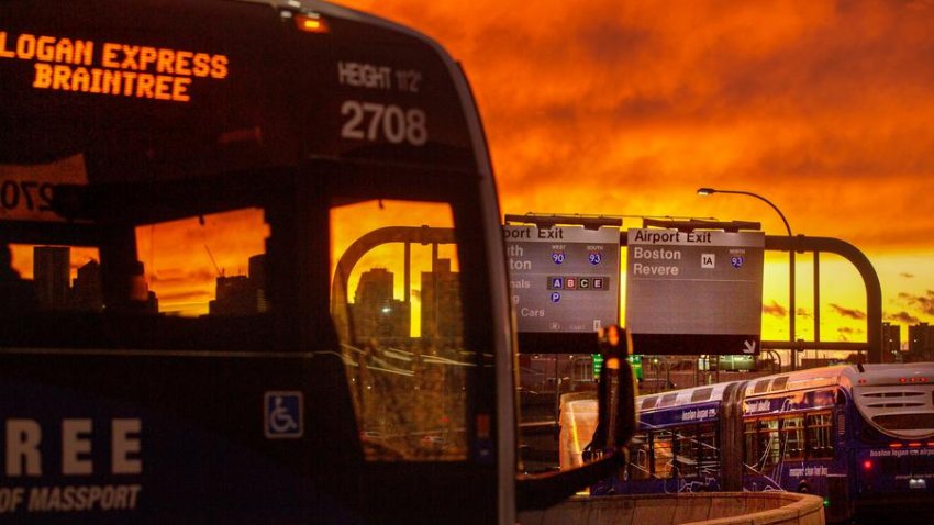 A Logan Express bus from Braintree delivers holiday travelers at Logan Airport as a fiery sunset ends the day.