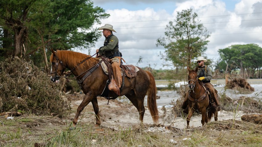 U.S. Customs and Border Protection officers help search and recovery crews scan the bank of the Guadalupe River for remains on July 9, 2025 in Center Point, Texas.