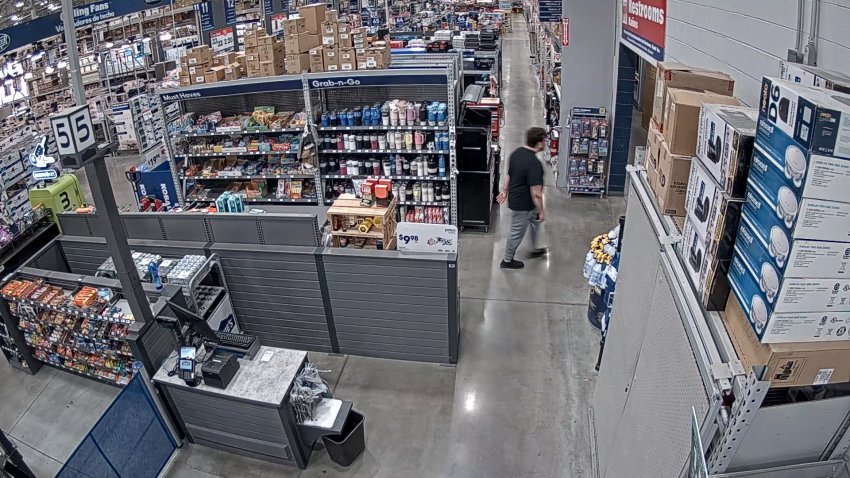 An image pulled from surveillance video at a Lowe's Home Improvement store. It shows a man in a dark shirt and grey sweatpants walking into the bathroom.