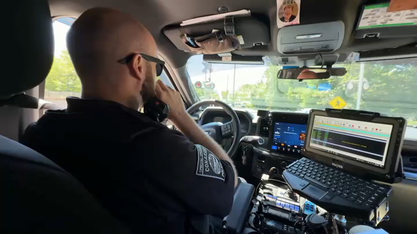 A Cohasset, Massachusetts, police officer speaks on the radio inside a cruiser on Tuesday, July 22, 2025.