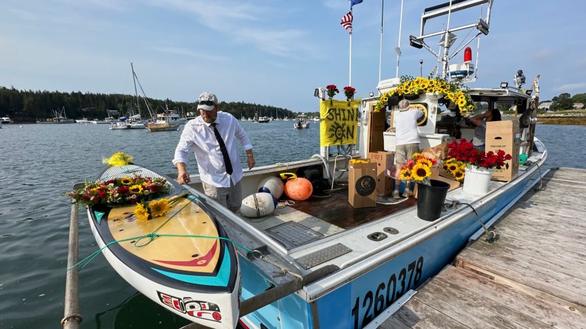 Lobsterman Josh Hupper adds flowers to Sunshine Stewart's paddleboard