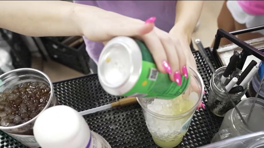 A dirty soda is mixed by a woman with pink nails.