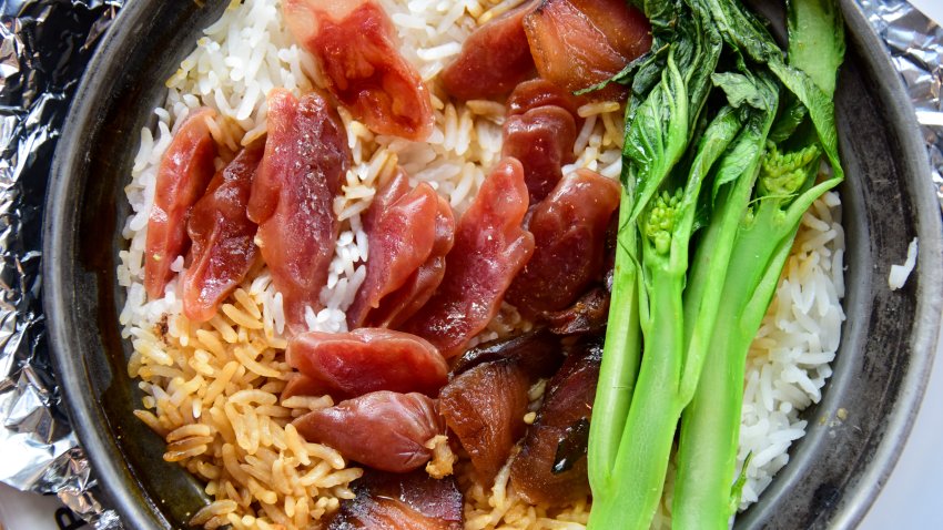 Close up of rice cooked in a clay pot with Cantonese sausage, Chinese broccoli and soy sauce