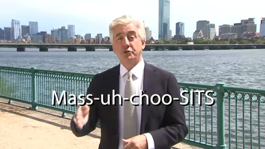 With Boston and the Charles River behind him, reporter Robert Goulston points to a graphic showing the pronunciation of "Massachusetts."