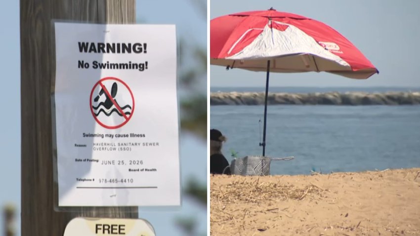 A sign that says "Warning! No swimming!" posted at a beach by the Merrimack River, which is dealing with a sewage overflow, on Tuesday, June 30, 2026. Next to it is an umbrella by the water.