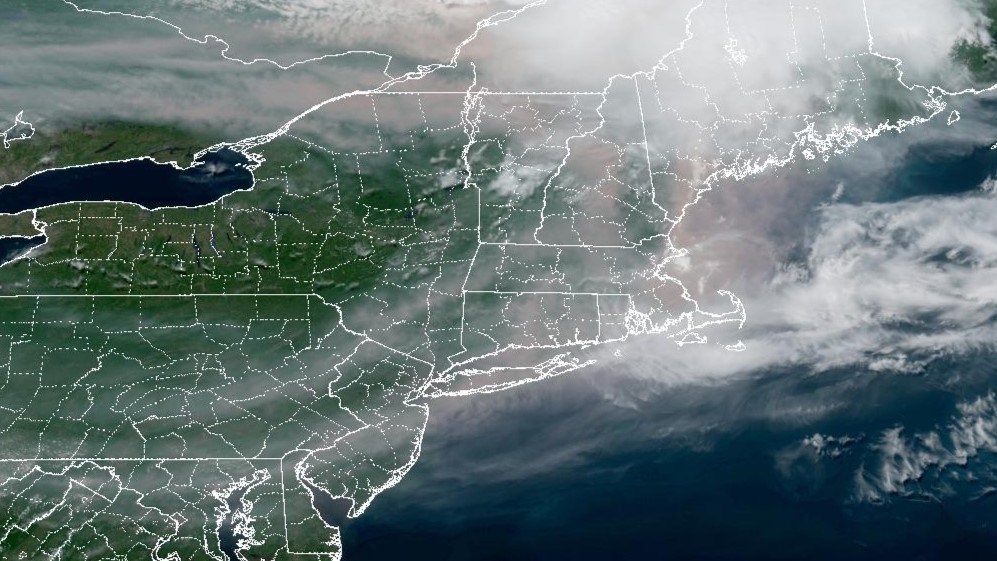 A satellite view of the Northeast U.S. on Tuesday, July 14, 2026. Wildfire smoke can be seen — a darker color mixed in with the white of the clouds.