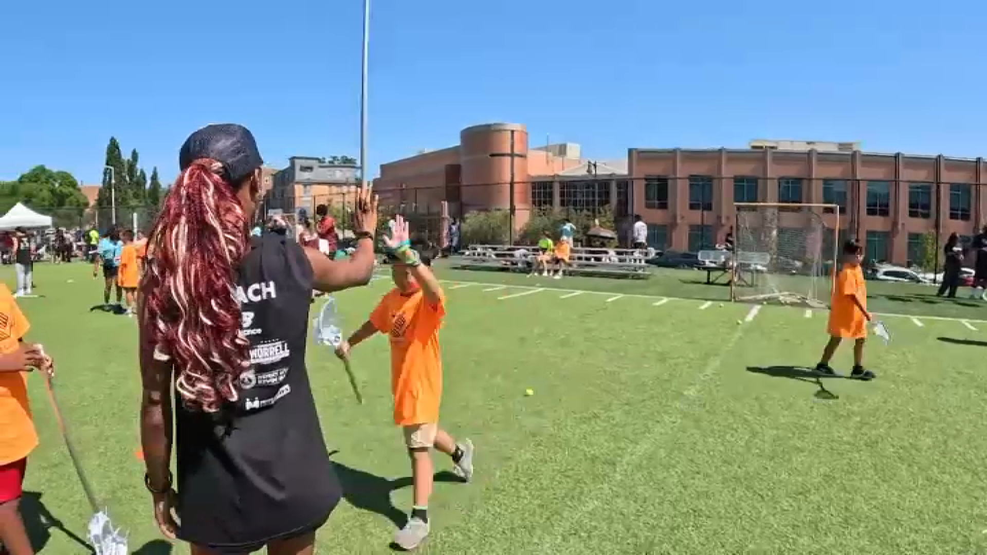 Naveah Martin gives a high five at a Harlem Lacrosse practice in East Boston on Tuesday, Aug. 4, 2026.