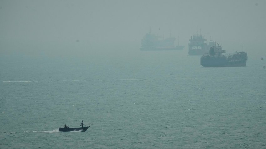 A motorboat travels past commercial vessels anchored amid haze in the Strait of Hormuz off Bandar Abbas, Iran, Monday, Sept. 7, 2026.