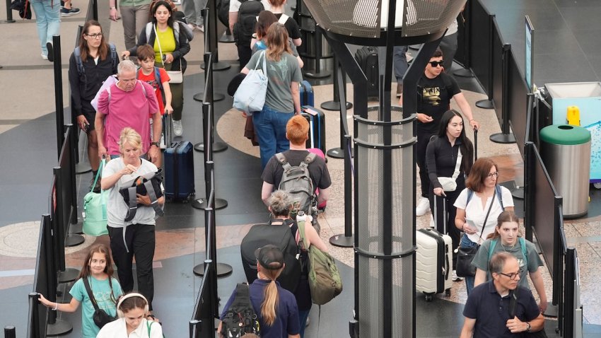 FILE -Travelers queue up to pass through the south security checkpoint in Denver International Airport Wednesday, July 2, 2025, in Denver.