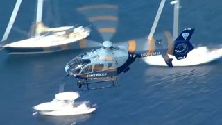 A Massachusetts State Police helicopter above Manchester-by-the-Sea on Monday, Oct. 5, 2026, amid a search for a missing man in a deadly boat crash.